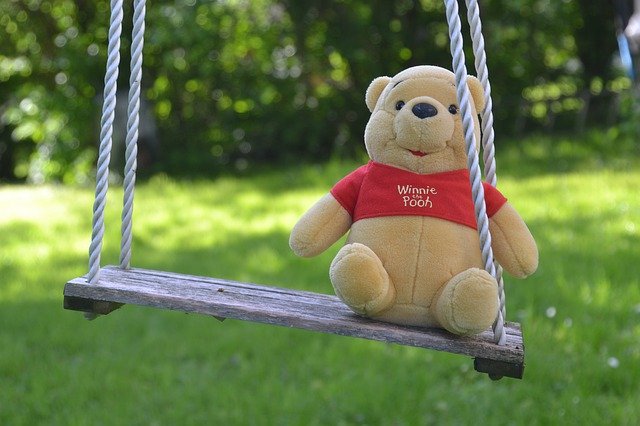 Winnie the Pooh stuffed animal on an outside swing